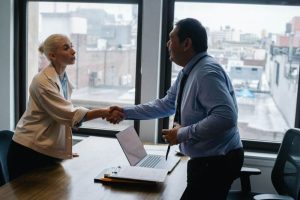 Two people shaking hands over a desk